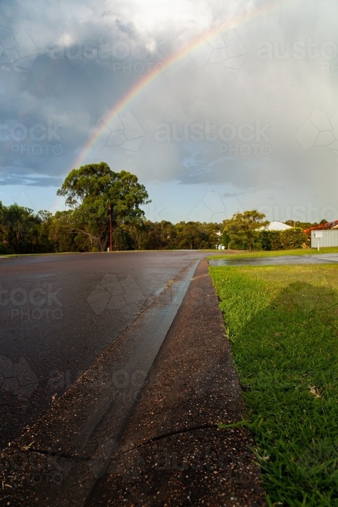 Rainwater running down gutter to stormwater drain in street - Australian Stock Image