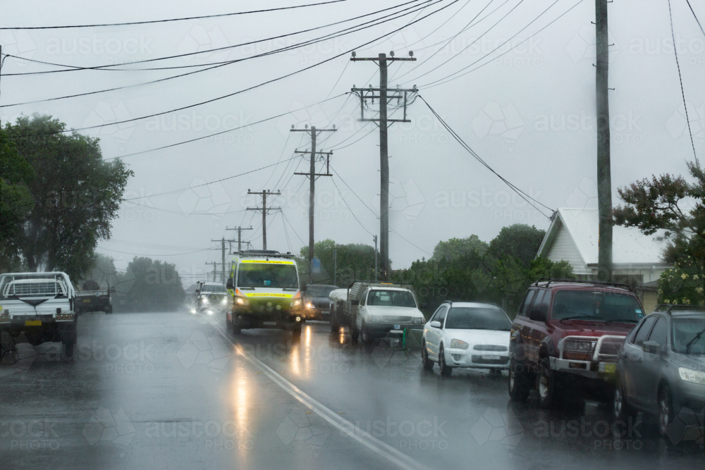 Rainy stormy day with ambulance emergency service vehicle driving on slippery wet road - Australian Stock Image