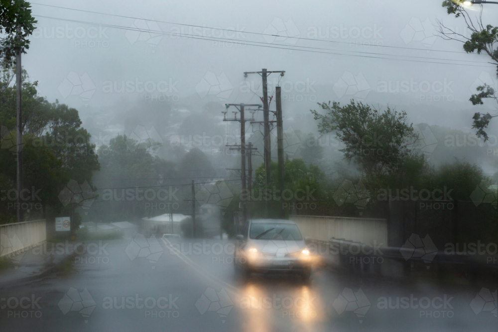 Rainy stormy day with vehicles driving on slippery wet road with low visibility conditions - Australian Stock Image