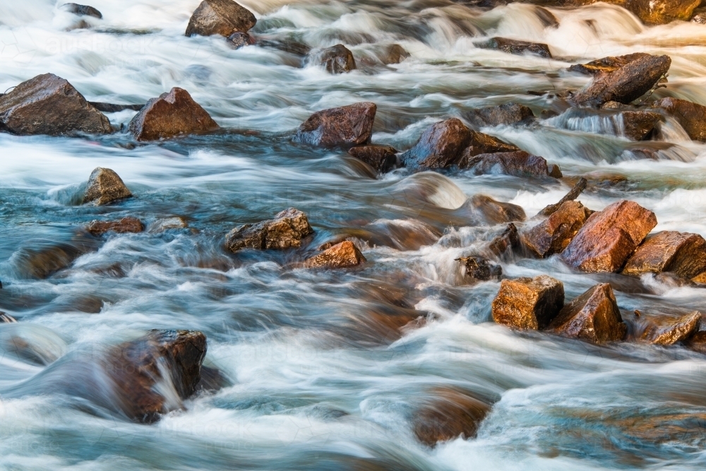 Image of Rapid water moving along a rocky river bed - Austockphoto