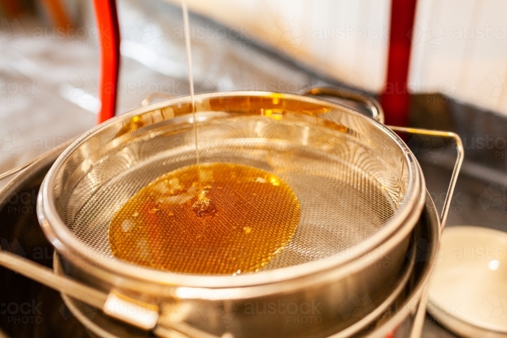 raw honey dripping from honey extractor machine - honey harvest - Australian Stock Image