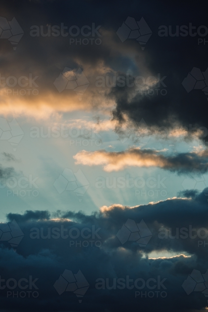 Rays of sunlight through dark clouds in the sky - Australian Stock Image