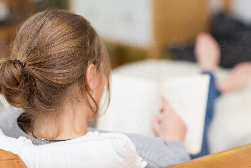 Reading a book with her feet up - Australian Stock Image