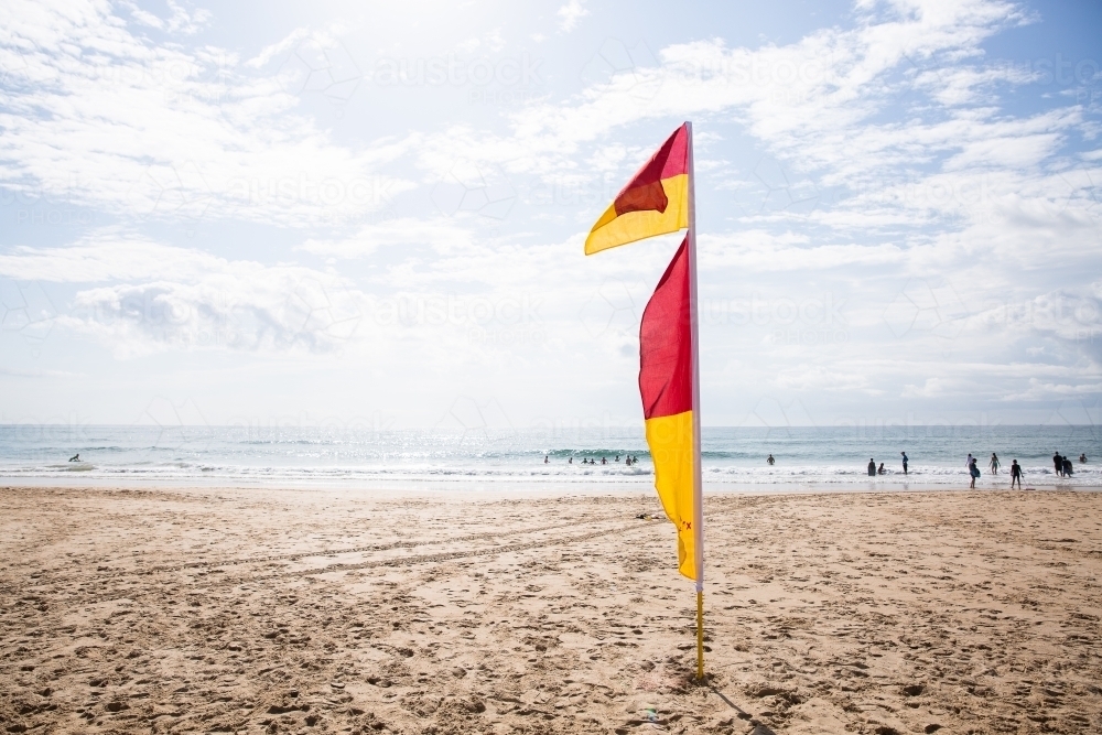 red and yellow flags at the beach on a sunny day - Australian Stock Image