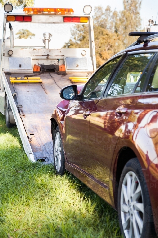 Red car after a front end collision road accident being towed onto a tow truck - Australian Stock Image