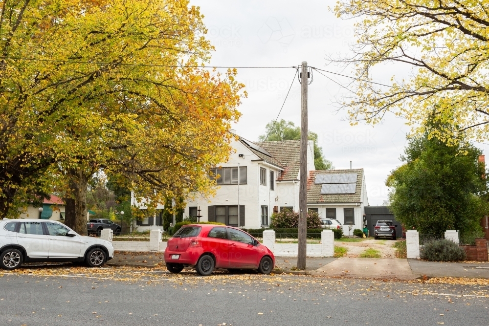 red car parked on street in autumn at 45 degree angle parking - Australian Stock Image