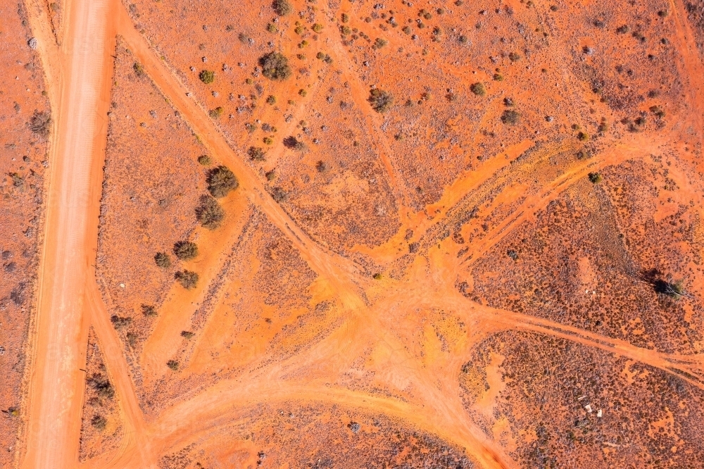 red outback ground criss-crossed with tracks and roads - Australian Stock Image