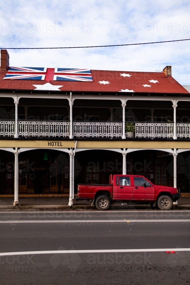 Red ute parked outside of Aussie pub with anti-lockdown australian red ensign flag on roof - Australian Stock Image