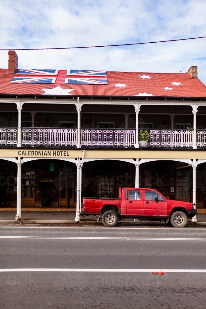 Red ute parked outside of Aussie pub with anti-lockdown australian red ensign flag on roof - Australian Stock Image