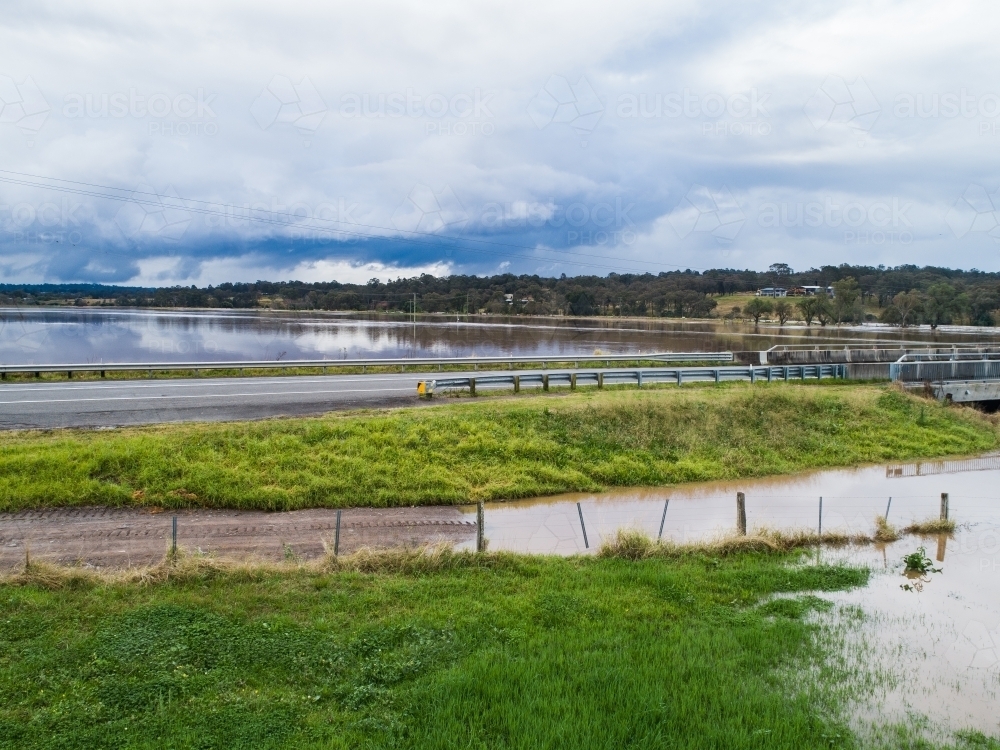 Redbournberry bridge near Singleton surrounded by flood water with storm rain clouds in sky - Australian Stock Image