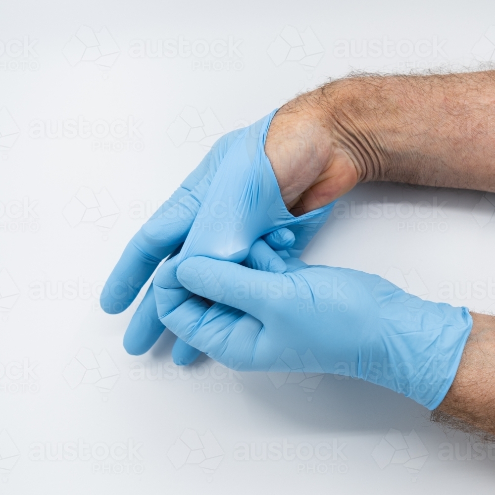 Removing blue medical gloves - Australian Stock Image