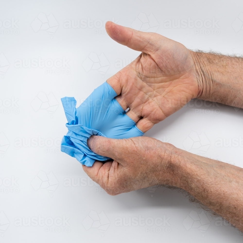 Removing blue medical gloves - Australian Stock Image