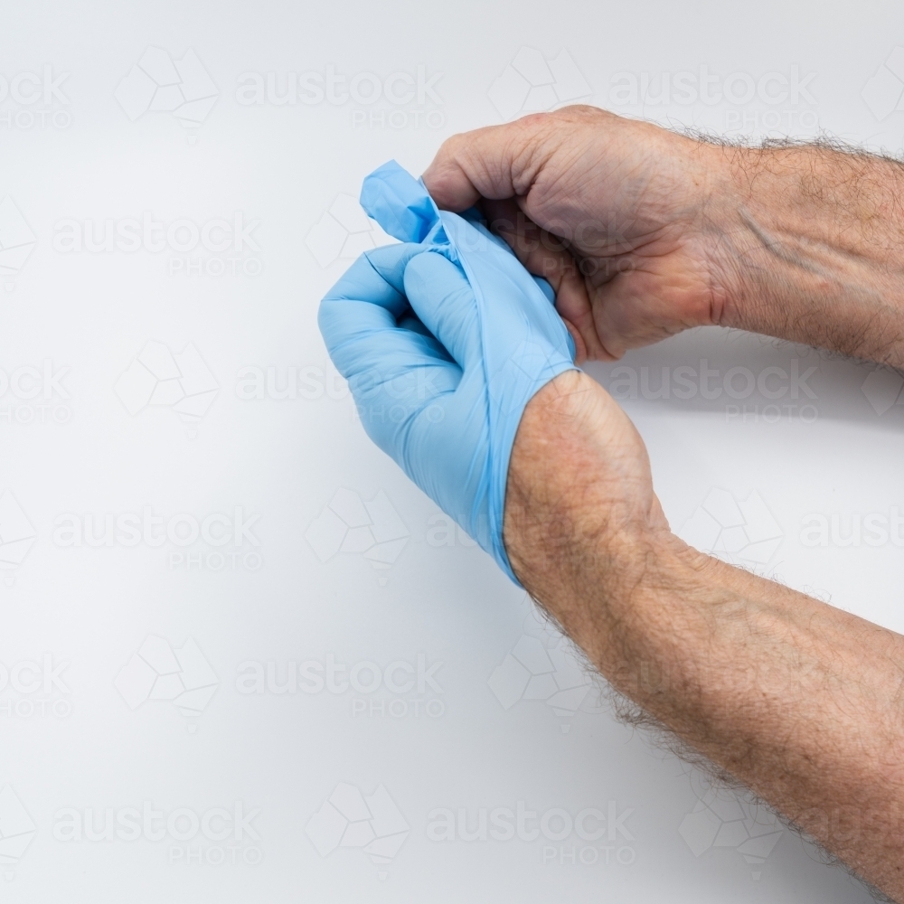 Removing blue medical gloves - Australian Stock Image