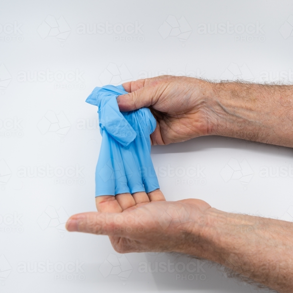 Removing blue medical gloves - Australian Stock Image