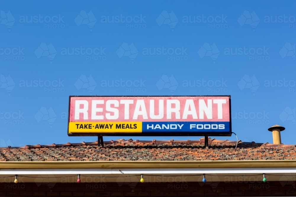 Restaurant sign on tiled roof with blue sky - Australian Stock Image