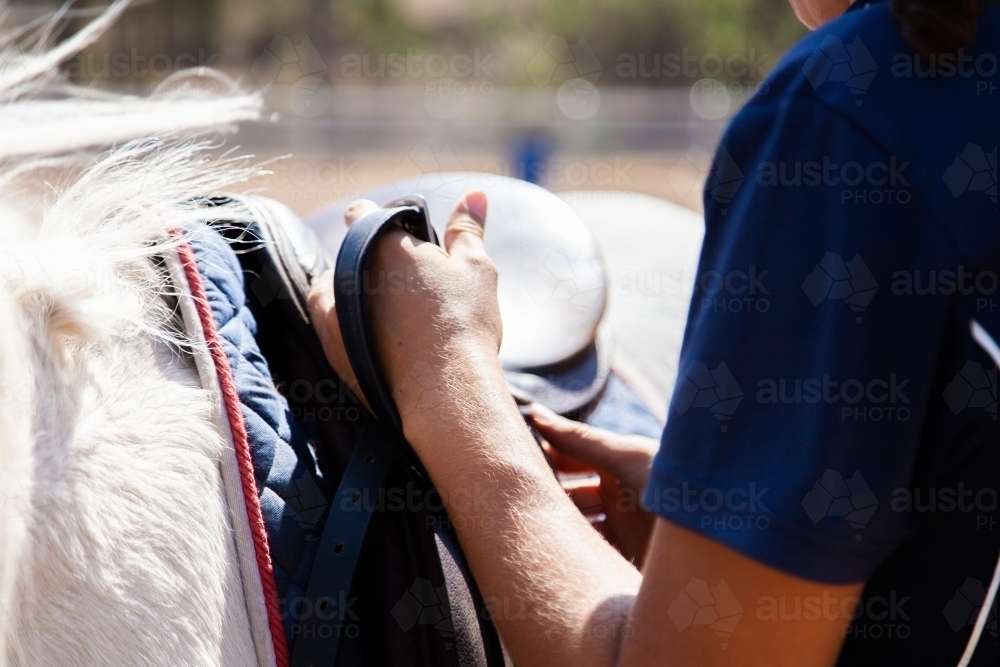 riding instructor changing stirrups on saddle - Australian Stock Image