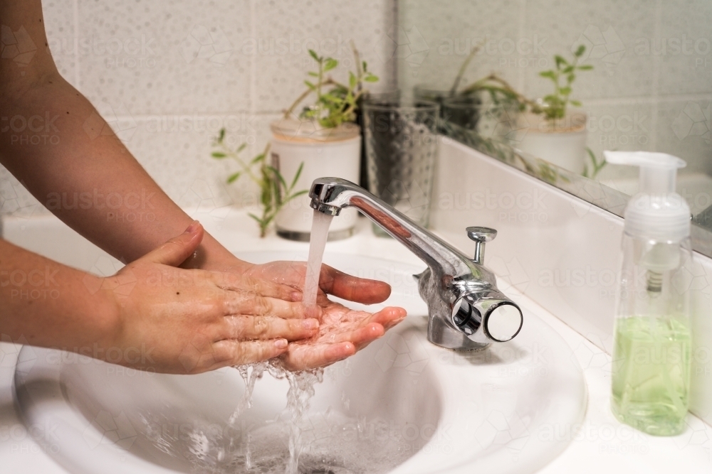 rinsing hands after washing - Australian Stock Image