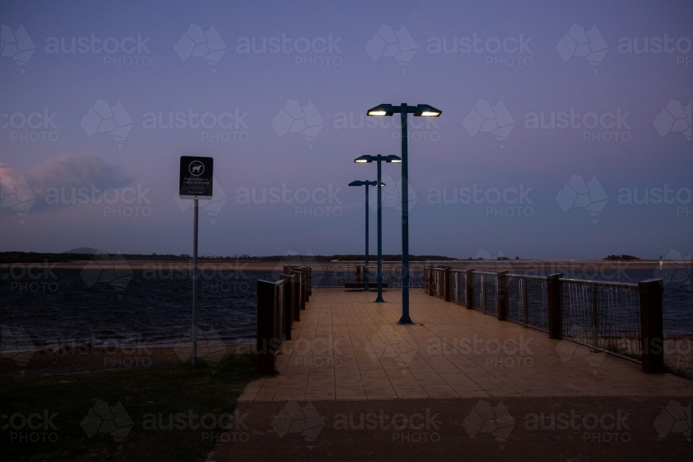 river jetty with lights on in dark after dusk - Australian Stock Image