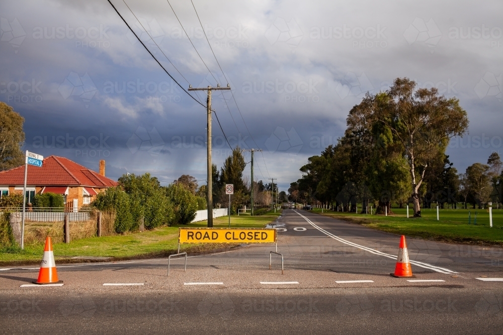 Road closed sign in town during flood with more rain in distance - Australian Stock Image