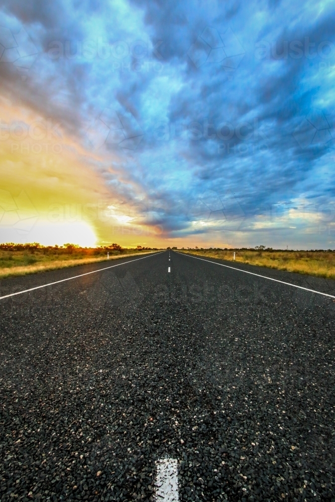 Road leading to horizon with dramatic sky - Australian Stock Image