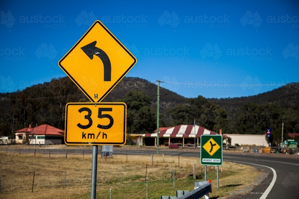 Road sign showing sharp bend ahead recommended speed 35 km per hour - Australian Stock Image