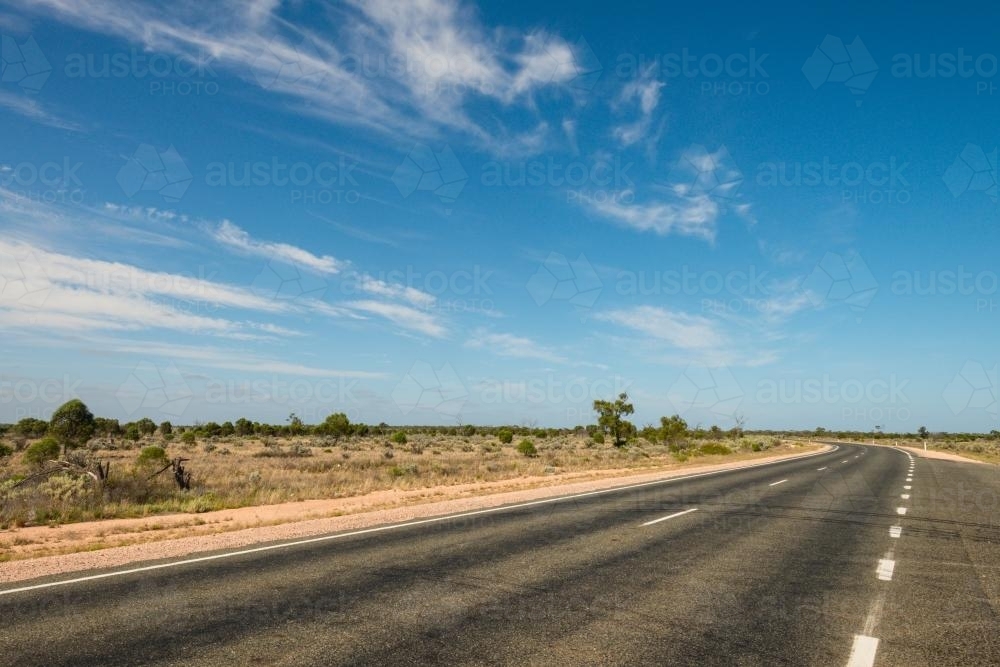 Road trip across the Nullarbor, long empty road stretch ahead. - Australian Stock Image