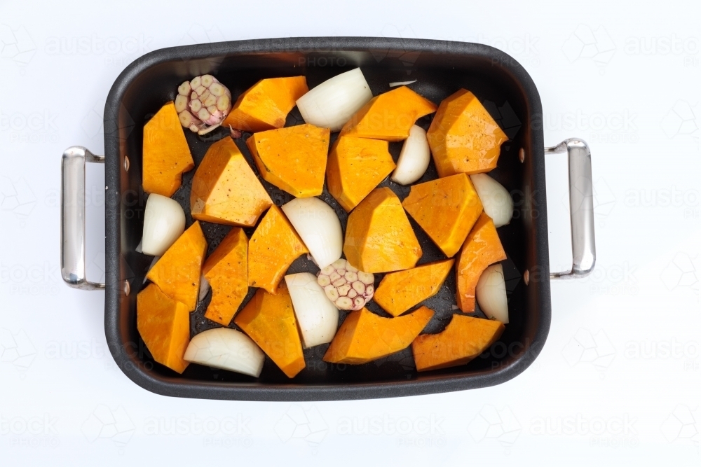 Roasting tray with pumpkin, onion and garlic - Australian Stock Image