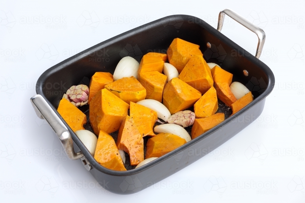 Roasting tray with pumpkin, onion and garlic - Australian Stock Image