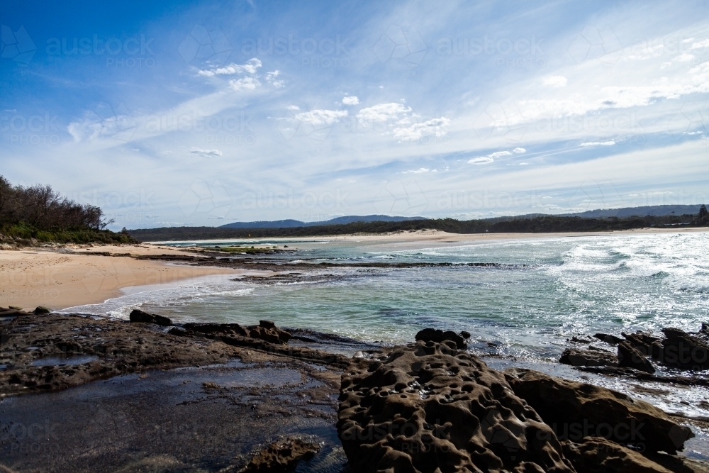 Image of Rocks and ocean waves washing up on deserted beach of Crampton ...