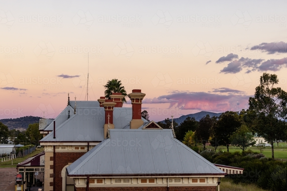 Rooftop of the historic Mudgee Railway Station with pink and purple twilight sky - Australian Stock Image