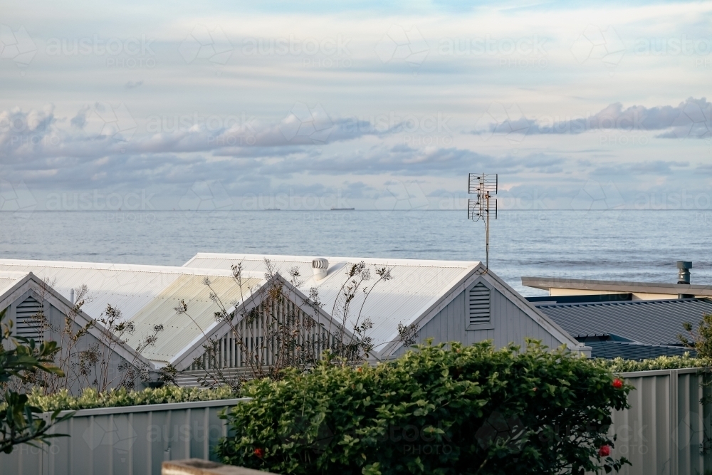 Image of Row of pitched beach house roofs with sea in background in ...