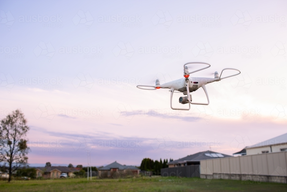 RPA drone flying over edge of suburban area at dusk - Australian Stock Image