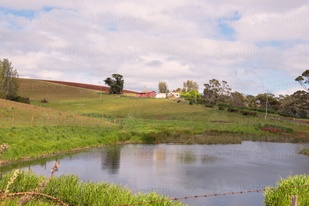 Rural landscape with dam and with farm buildings in the distance - Australian Stock Image