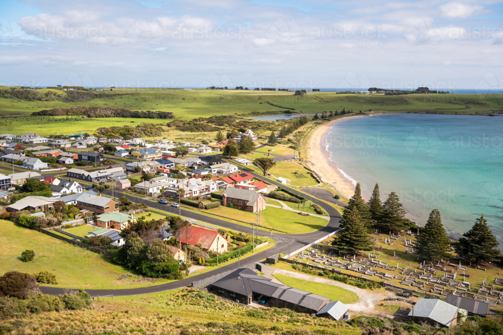 Rural valley landscape with farm buildings and hills in the distance along the shore - Australian Stock Image
