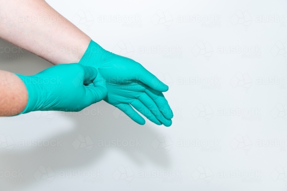 Safely removing green surgical gloves - Australian Stock Image