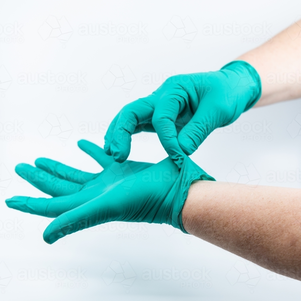 Safely removing green surgical gloves - Australian Stock Image