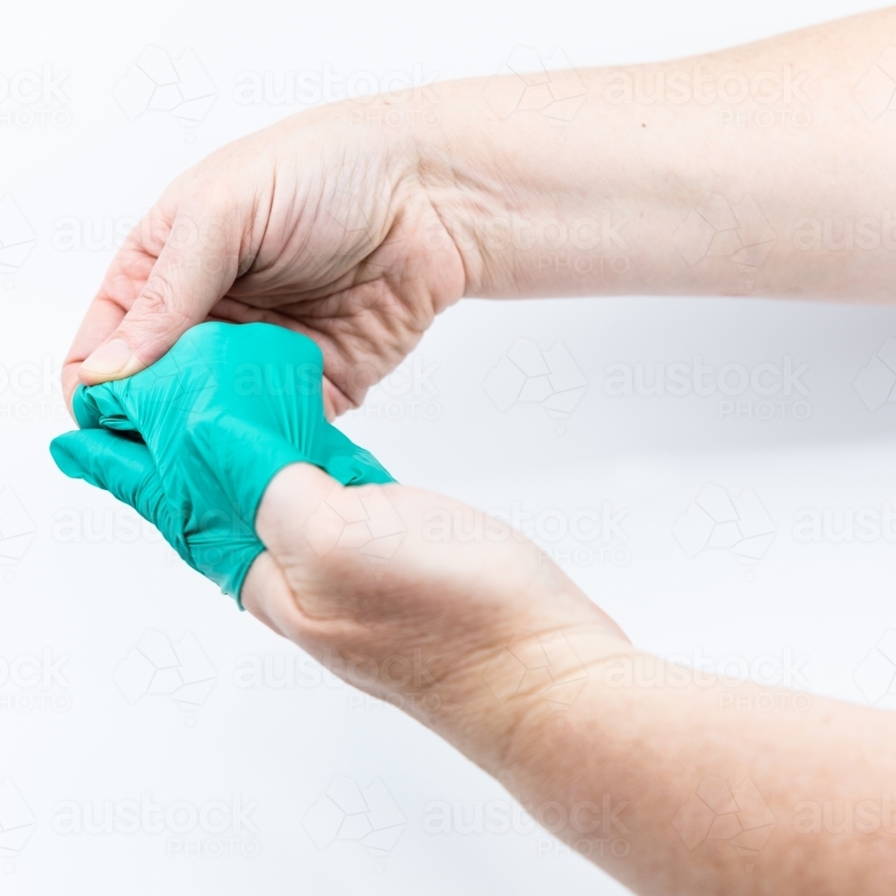 Safely removing green surgical gloves - Australian Stock Image