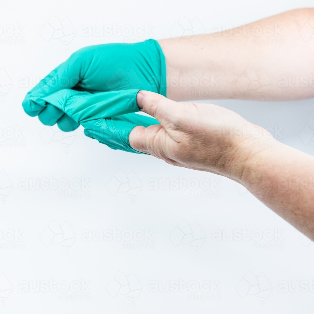 Safely removing green surgical gloves - Australian Stock Image