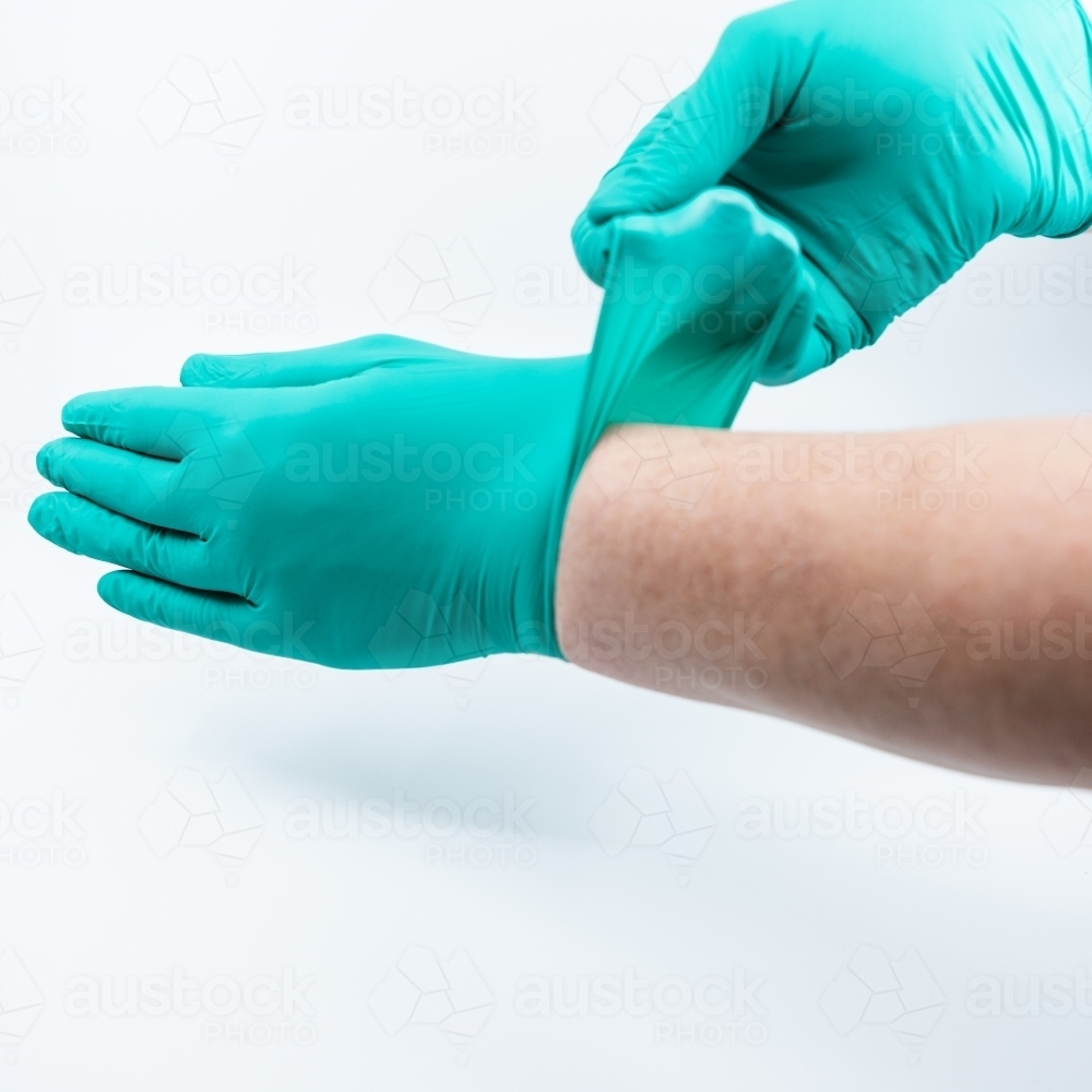 Safely removing green surgical gloves - Australian Stock Image