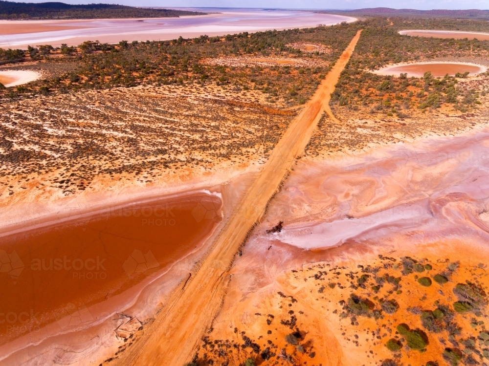 Salt lake with road through outback landscape - Australian Stock Image