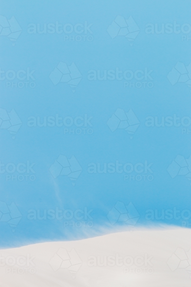 sand drifting on white dunes under blue sky vertical - Australian Stock Image