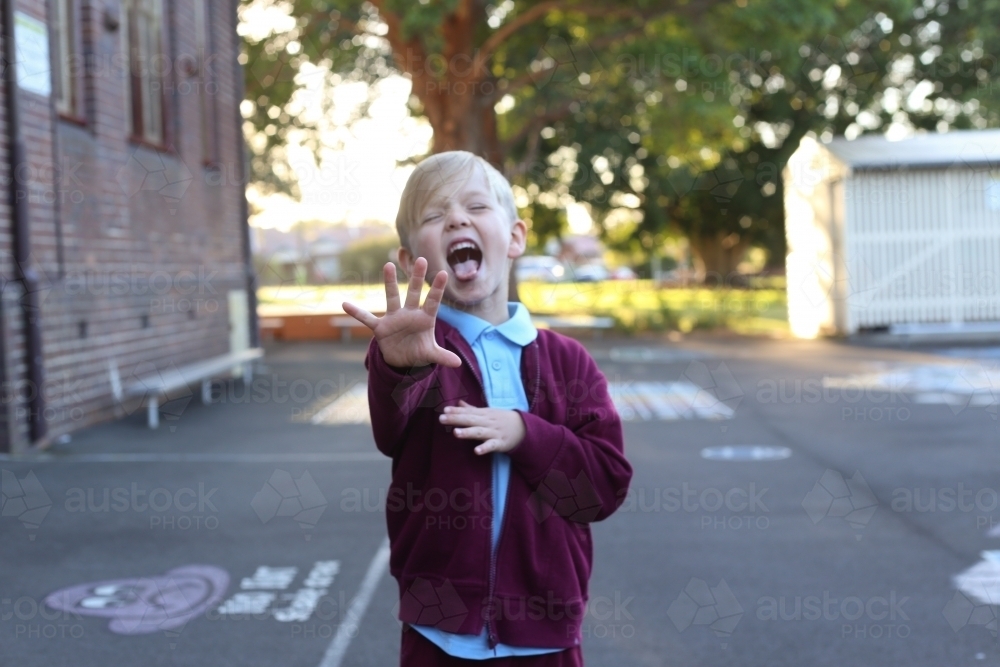 School boy being silly sticking his tongue out in the playground - Australian Stock Image