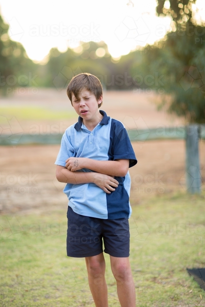 Image of School boy looking pained - Austockphoto