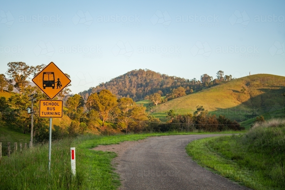 School bus turning sign on rural country road at sunset - Australian Stock Image