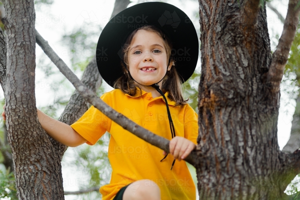 School child in Australia climbing up a tree smiling - Australian Stock Image