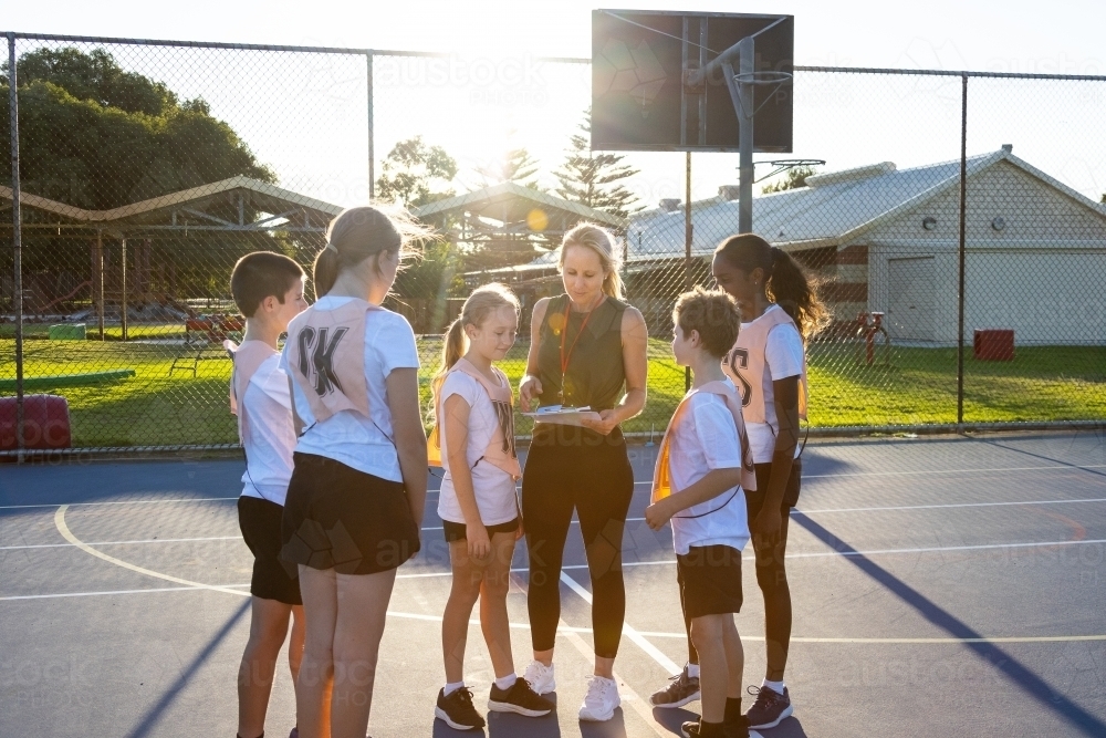 school children at netball training with coach who is a mum - Australian Stock Image