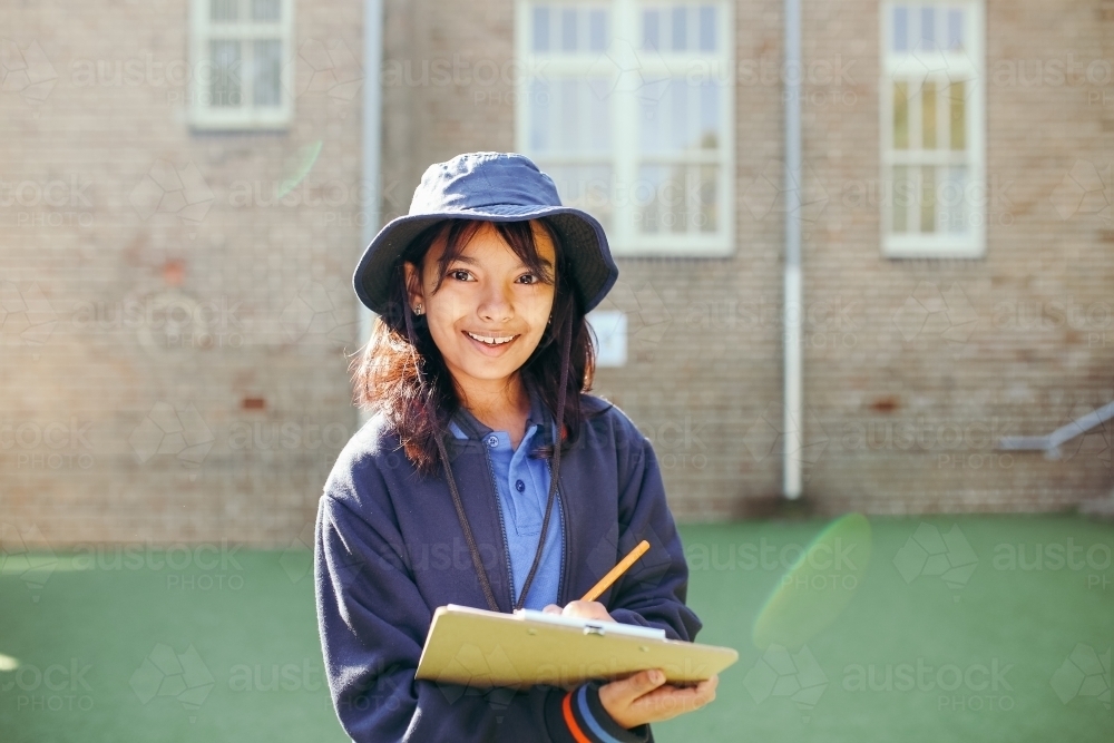 School student standing holding a clipboard looking at the camera - Australian Stock Image