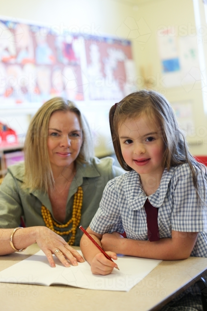 School teacher helping child with her writing work - Australian Stock Image