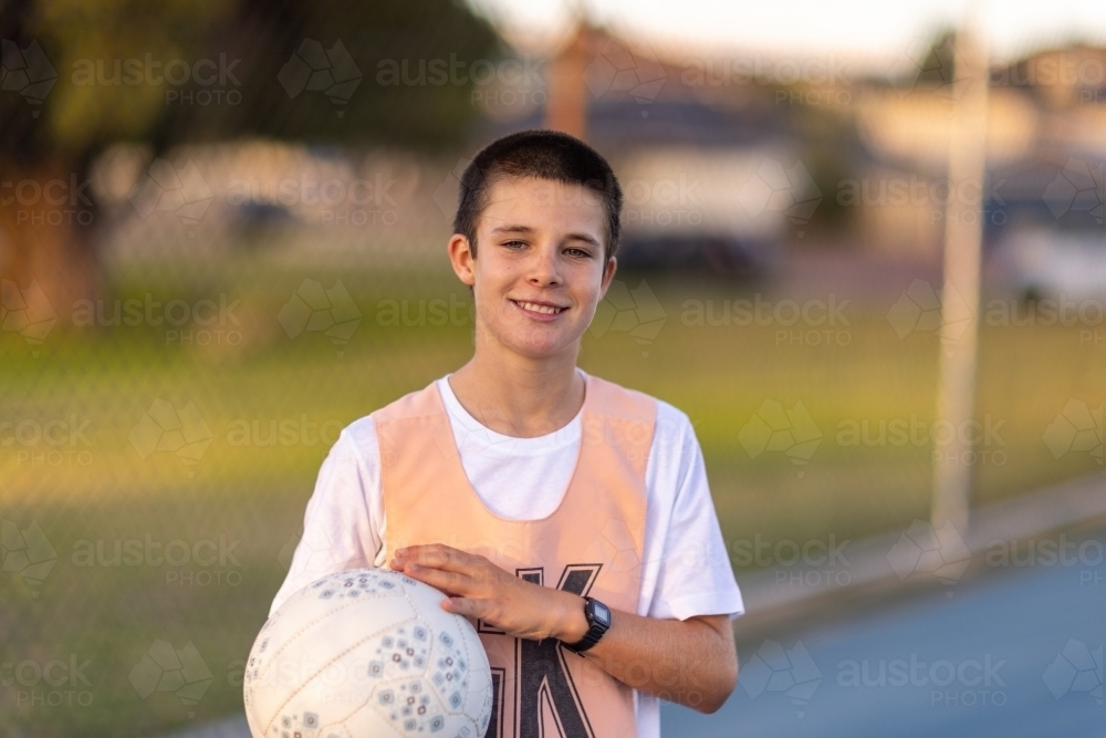 schoolboy on court holding netball wearing netball bib - Australian Stock Image