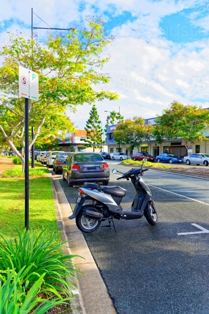 Scooter and cars parked on the side of the road in suburban area near shopping centre - Australian Stock Image